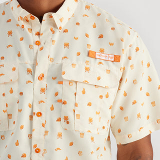 Close-up of a cream-colored shirt with orange patterns and a brand label on a white background
