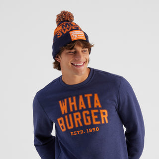 Person wearing a navy sweatshirt with 'WHATA BURGER' text and an orange and navy beanie.