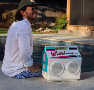 man sitting by kool tunes cooler next to swimming pool