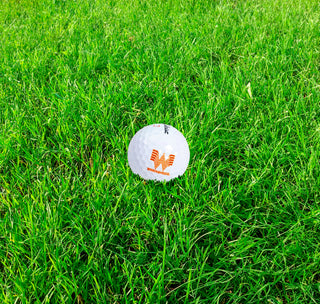 View Titleist Velocity Golf Balls with Whataburger Logo sitting on the grass