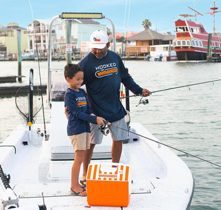 view father and son fishing while wearing hooked on whataburger shirts.