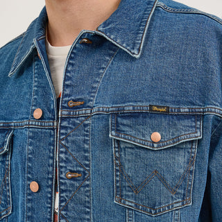 Close-up of the front pocket details on the Wrangler® x Whataburger® Men's Laser Denim Jacket – A close-up view of the Wrangler® x Whataburger® Men's Laser Denim Jacket’s chest pocket, featuring a "Wrangler" tag, signature W-shaped stitching, and a copper button.