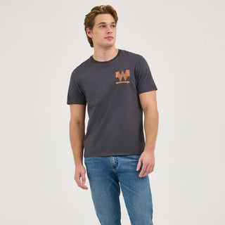 A full-body shot of the model styled in the Wrangler® x Whataburger® Ingredient T-Shirt with Wrangler jeans and classic white sneakers. The casual pose highlights the laid-back, everyday wearability of the design.