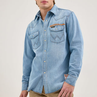 Front view of the Wrangler® x Whataburger® Men's Western Shirt – A male model wears the Wrangler® x Whataburger® Men's Western Shirt in light-wash denim, featuring pearl snap buttons, contrast stitching, and chest pockets with Wrangler’s signature W-shaped embroidery. The "WHATAWrangler" logo is embroidered above the left pocket.