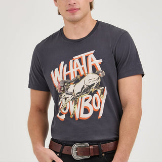 A male model poses in the Wrangler® x Whataburger® Cowboy Graphic Black T-Shirt, styled with black jeans, a brown belt, and cowboy boots. The front design of the cowboy and "WHATA COWBOY" text is visible.