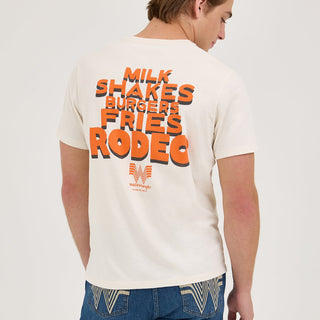 The back of the Wrangler® x Whataburger® Cowboy Graphic White T-Shirt is shown, featuring bold orange and black text reading "MILK SHAKES BURGERS FRIES RODEO" with the Whataburger Flying W logo at the bottom.