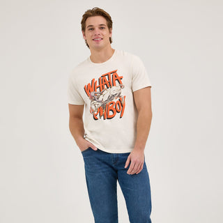 A full-body image of the model wearing the Wrangler® x Whataburger® Cowboy Graphic White T-Shirt, paired with straight-leg blue jeans and sneakers. He stands casually with a friendly smile.