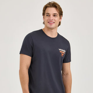 A model wearing the Wrangler® x Whataburger® Cowboy Burgers Black T-Shirt, standing facing the camera with hands at his sides. The small Wrangler® x Whataburger® chest logo is visible, adding a subtle yet stylish branding element.