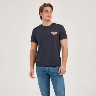 A full-body shot of the model wearing the Wrangler® x Whataburger® Cowboy Burgers Black T-Shirt, paired with classic Wrangler jeans and casual sneakers. The relaxed fit and soft fabric are visible, making it ideal for everyday wear.