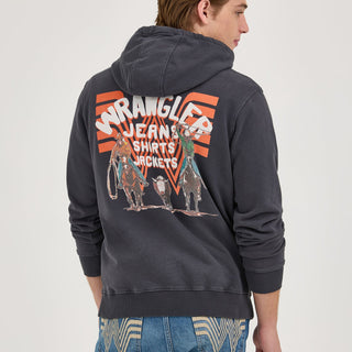 A male model showcasing the back of the Wrangler® x Whataburger® Faded Black Hoodie. The design features a Western-themed graphic with cowboys on horseback, a steer, and the Wrangler logo over the Flying W background in orange and blue.