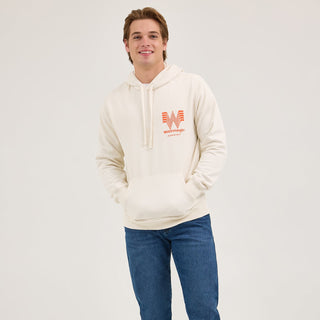 Full-body shot of a male model in the Wrangler® x Whataburger® Cream Hoodie – A male model wears the Wrangler® x Whataburger® Cream Hoodie paired with blue denim jeans and brown cowboy boots, showcasing a casual yet Western-inspired outfit.