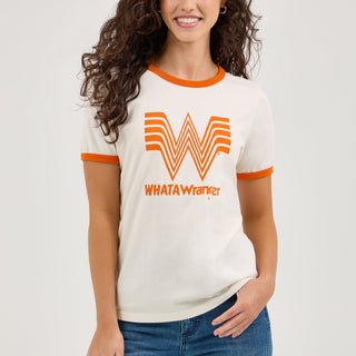 The model smiles while showcasing the Wrangler® x Whataburger® Women's Ringer Tee. She stands with one hand resting on her hip, emphasizing the vintage-inspired fit and orange accent details.