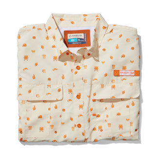 Folded cream colored button down shirt with orange patterns on a white background