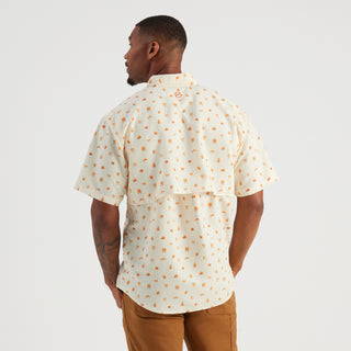 Man wearing a patterned shirt and brown pants on a white background