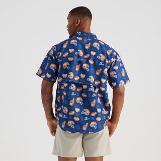 Man wearing a blue patterned shirt and beige shorts on a white background