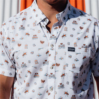 Man wearing a white short-sleeve button-up shirt covered in a Western-themed Whataburger pattern.