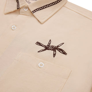 Beige shirt with black embroidered design on a white background