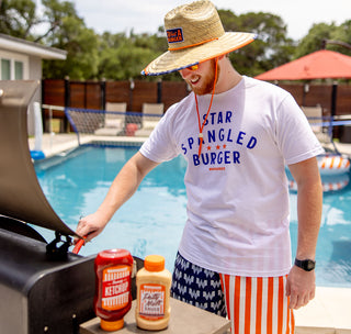 View man grilling by a pool with Whataburger products
