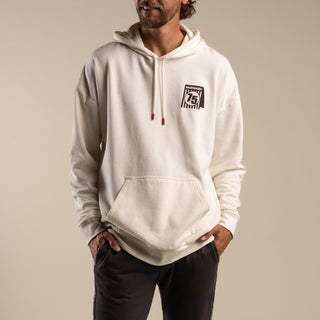 Man wearing a white hoodie with a logo on a beige background