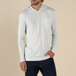 Man wearing a light gray hoodie and dark jeans on a beige background