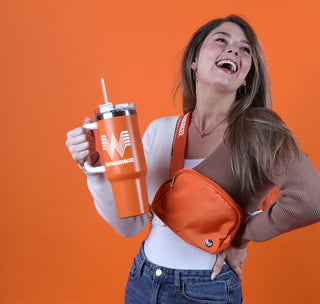 view woman holding 40 oz whataburger water bottle, and wearing the orange whataburger belt bag