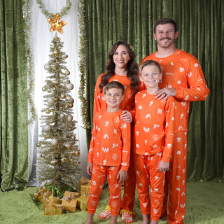view adult and youth pajama sets being worn by family standing next to tree 