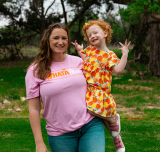 view mom holding daughter wearing the whatamama tee in a park