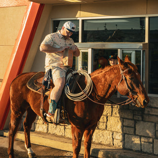 view man on horse in drive thru wearing the texas burger hat