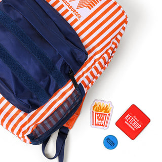 The fries patch, a blue "Special" day dot patch, and a red "Fancy Ketchup" square patch with white text sit next to the orange and white striped backpack with navy blue zipper pocket.