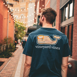 man wearing vineyard vines shirt in lively brick alleyway with string lights