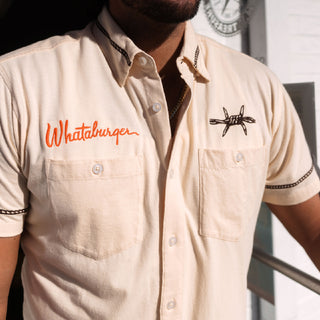 Beige shirt with 'Whataburger' logo worn by a person, with a clock in the background.