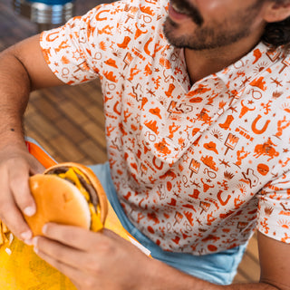 Person wearing a patterned shirt holding a burger