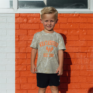 Child standing in front of orange and white striped brick building wearing Youth WHATA Drifter Camo 1950 Vintage Washed Tee.