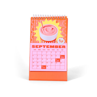 Calendar with a pink and orange design featuring a strawberry milkshake, on a white background.