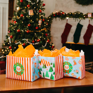 Three Whataburger holiday gift bags with striped, Christmas tree and wreath designs.