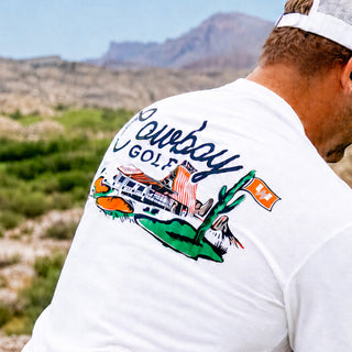 Man wearing white Cowboy golf t-shirt in front of desert background.
