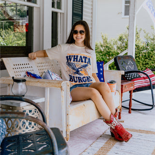 Woman sitting on a porch wearing a 'WHATABURGER' t-shirt and red cowboy boots.