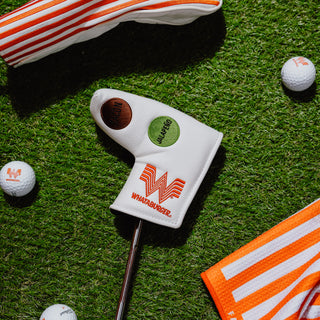 Day Dot Blade Putter Cover with Whataburger logo and Day Dots on grass with golf balls and towels