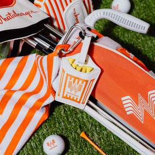 Golf bag with golf balls and French Fry Golf Tee Set on a grassy surface.