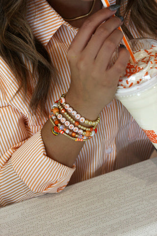 View woman's wrist wearing Whataburger Erimish Bracelet Stack and drinking Whataburger Birthday Shake