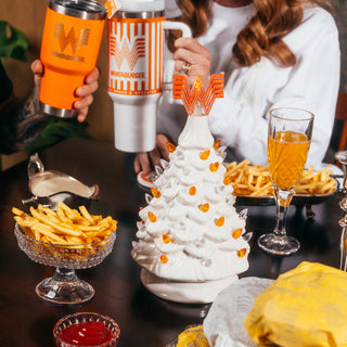 View Whataburger White Ceramic Tree on holiday dinner table. Tree is surrounded by Whataburger fries, burgers, condiments and other drinkware. 