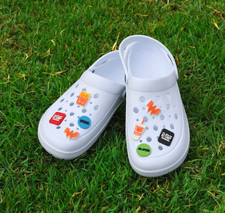 View Fancy and Spicy Shoe Charm Pack Featuring Blue Special Day Dot, Jalapeno day dot, Flying W, Fry Box, Drink, Spicy and Fancy Ketchup Charms placed onto white shoe on top of green grass.