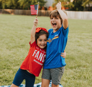 view children waving the american flag while wearing whataburger fancy tee and retro stripe tee.